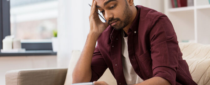 financially stressed man looking at calculator